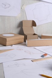 Creating packaging design. Drawings, boxes and stationery on light table, closeup