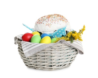 Basket with delicious Easter cake, dyed eggs and flowers on white background