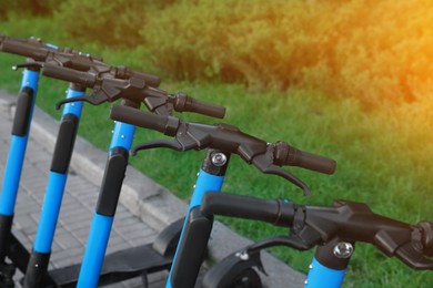 Photo of Many modern electric scooters on city street, closeup. Rental service