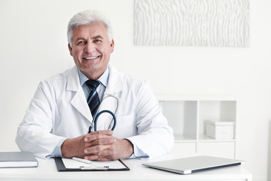 Portrait of senior doctor in white coat at workplace