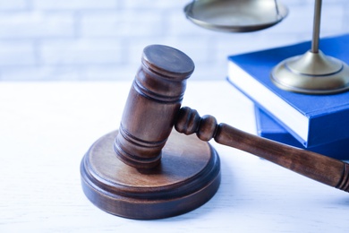 Wooden gavel, scales of justice and books on table, closeup. Law concept