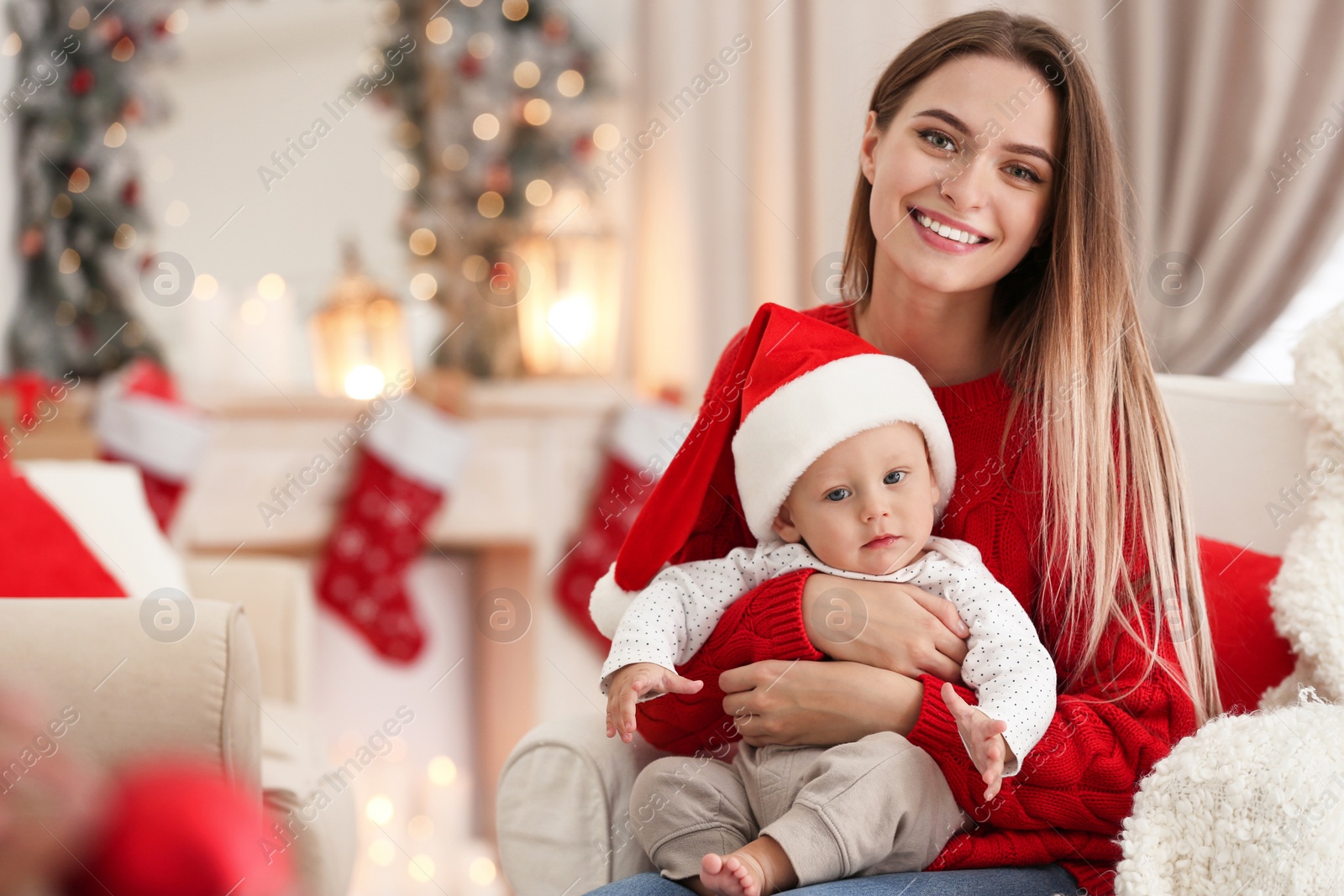 Photo of Happy mother with cute baby in room decorated for Christmas holiday