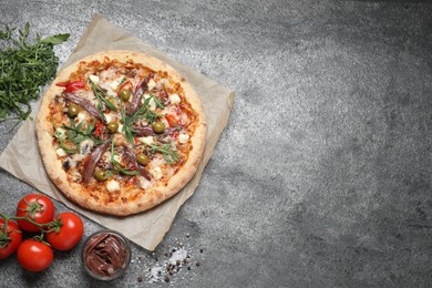 Tasty pizza with anchovies and ingredients on grey table, flat lay. Space for text