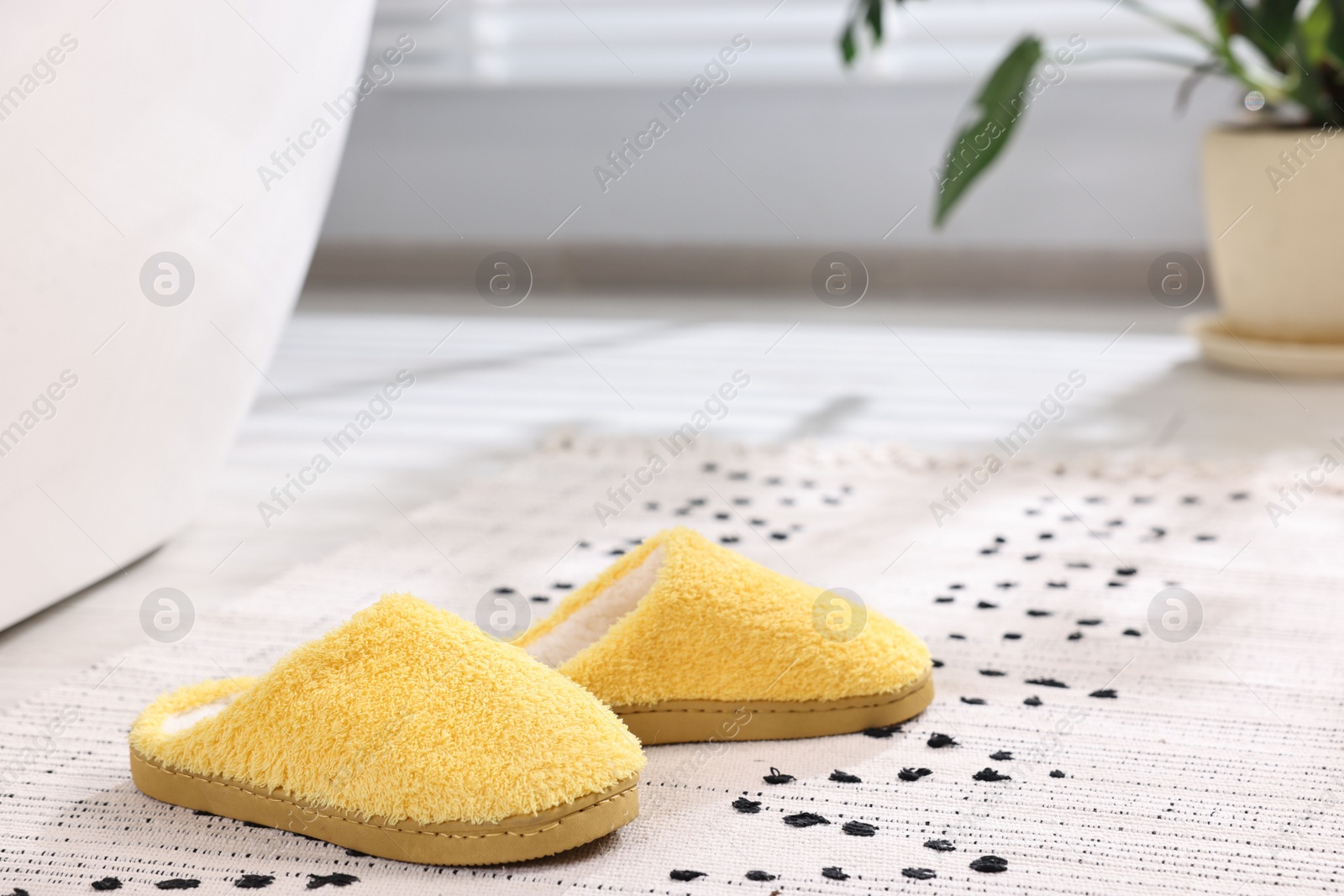 Photo of Yellow soft slippers on carpet at home, closeup