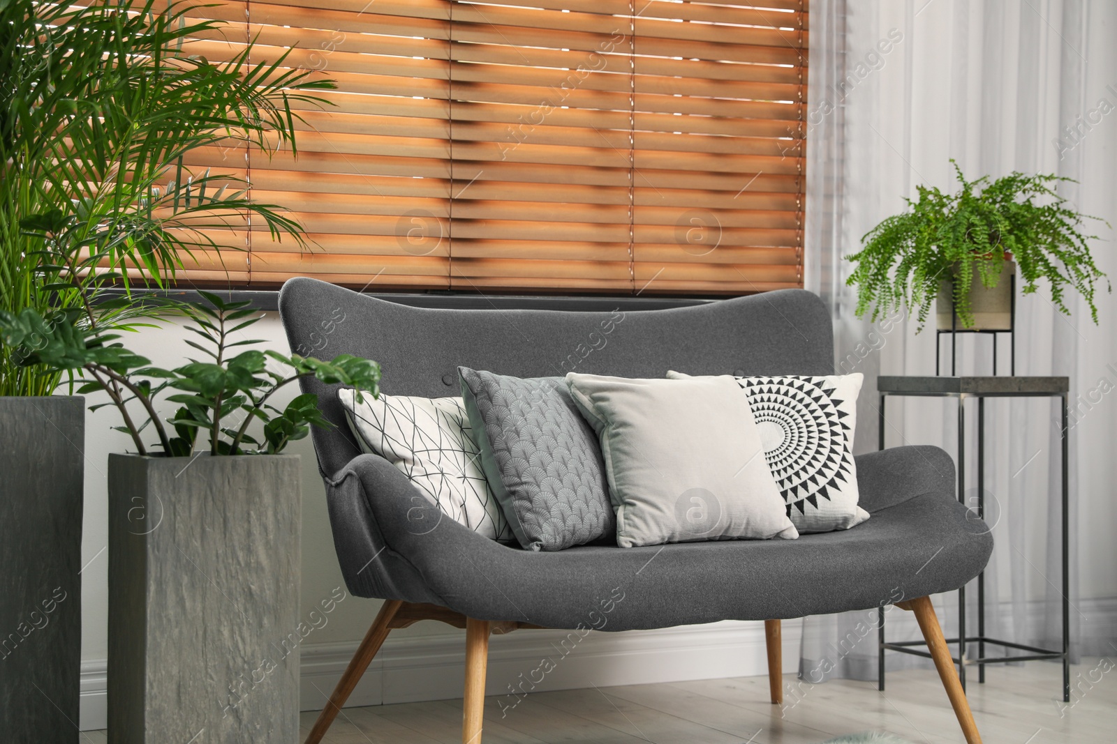 Photo of Stylish decorative pillows on grey couch indoors