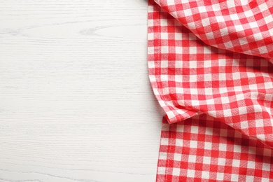 Checkered picnic tablecloth on wooden background, top view