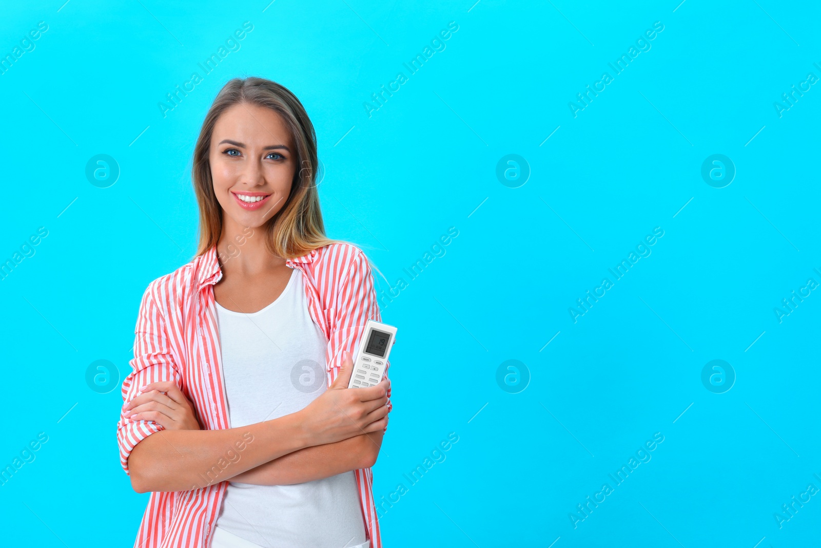 Photo of Young woman with air conditioner remote on blue background. Space for text