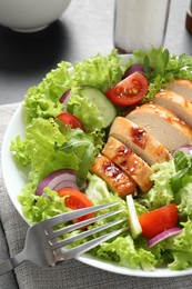 Eating delicious salad with chicken and vegetables at table, closeup