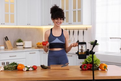 Photo of Smiling food blogger explaining something while recording video in kitchen