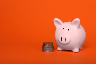 Photo of Ceramic piggy bank and coins on orange background, space for text. Financial savings