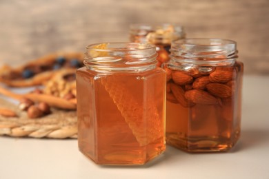 Photo of Jars with nuts and honey on beige table