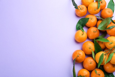 Fresh ripe tangerines with green leaves on lilac background, flat lay. Space for text