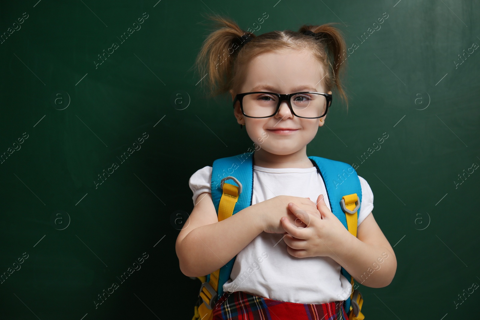 Photo of Cute little child wearing glasses near chalkboard. First time at school