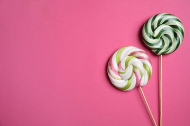 Sticks with colorful lollipops on pink background, flat lay. Space for text