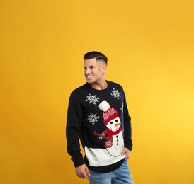 Handsome man in Christmas sweater on yellow background