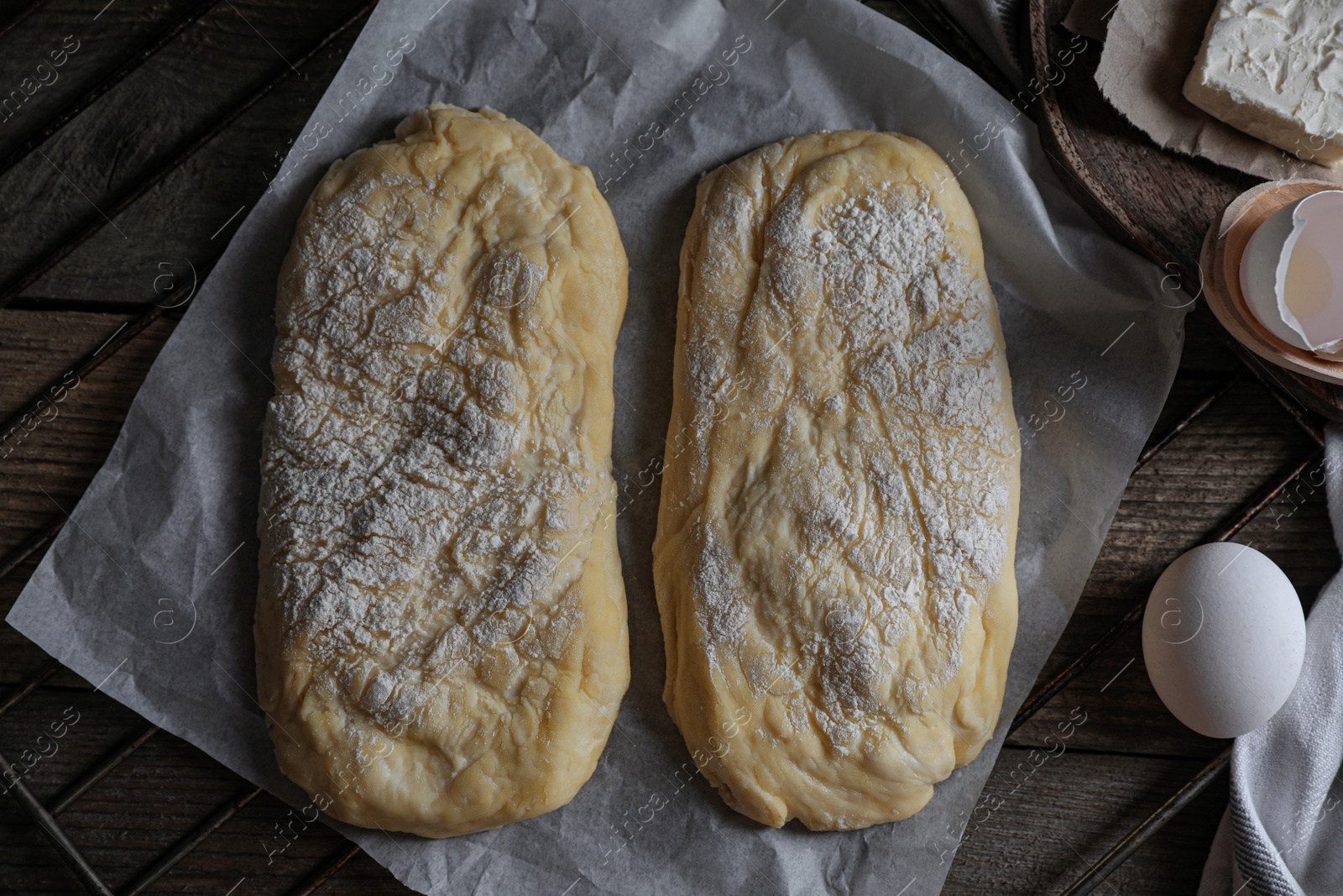 Photo of Raw dough for ciabatta and flour on wooden table, flat lay