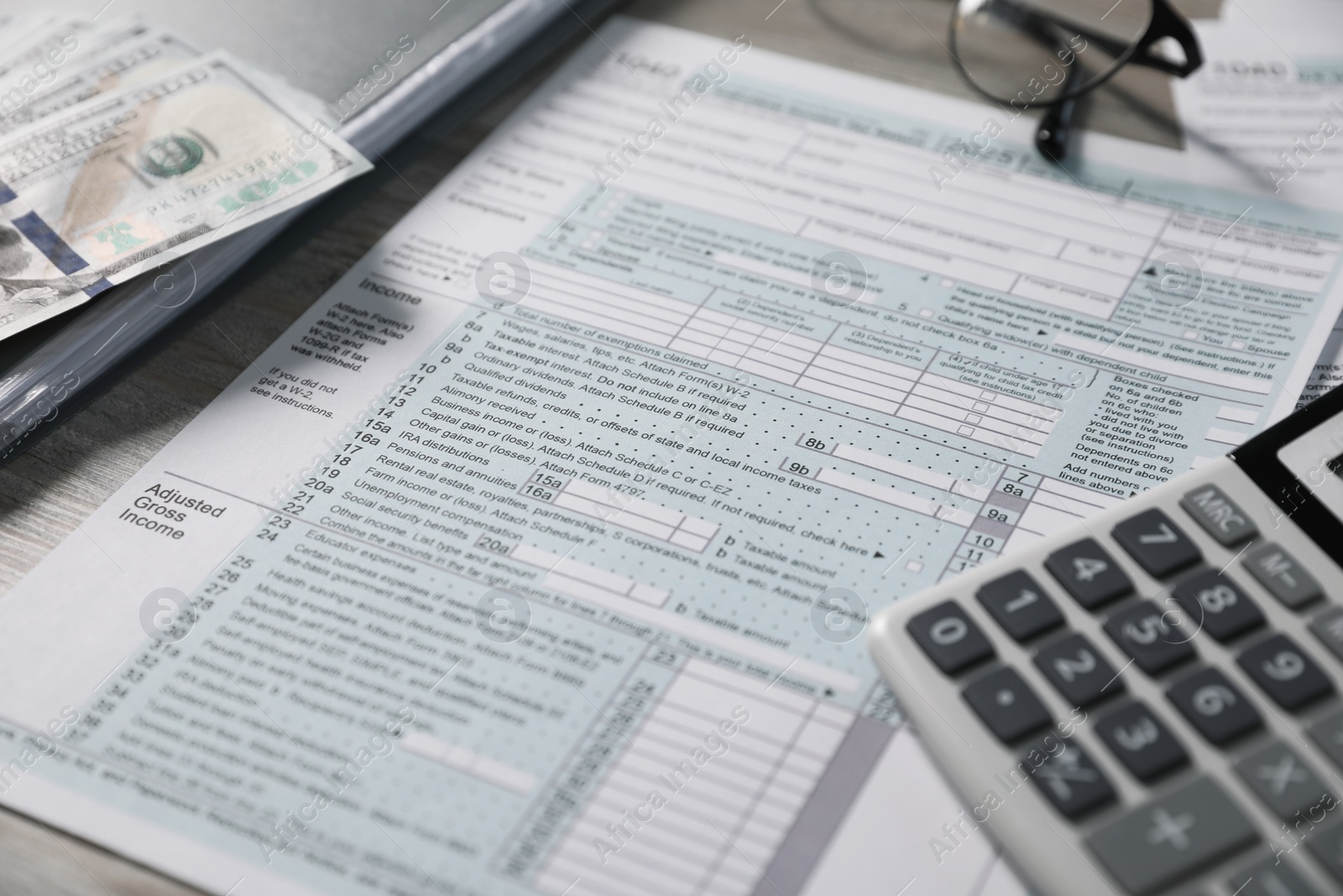 Photo of Payroll. Tax return forms, dollar banknotes and calculator on table, selective focus