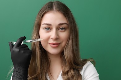 Portrait of cosmetologist with syringe on green background