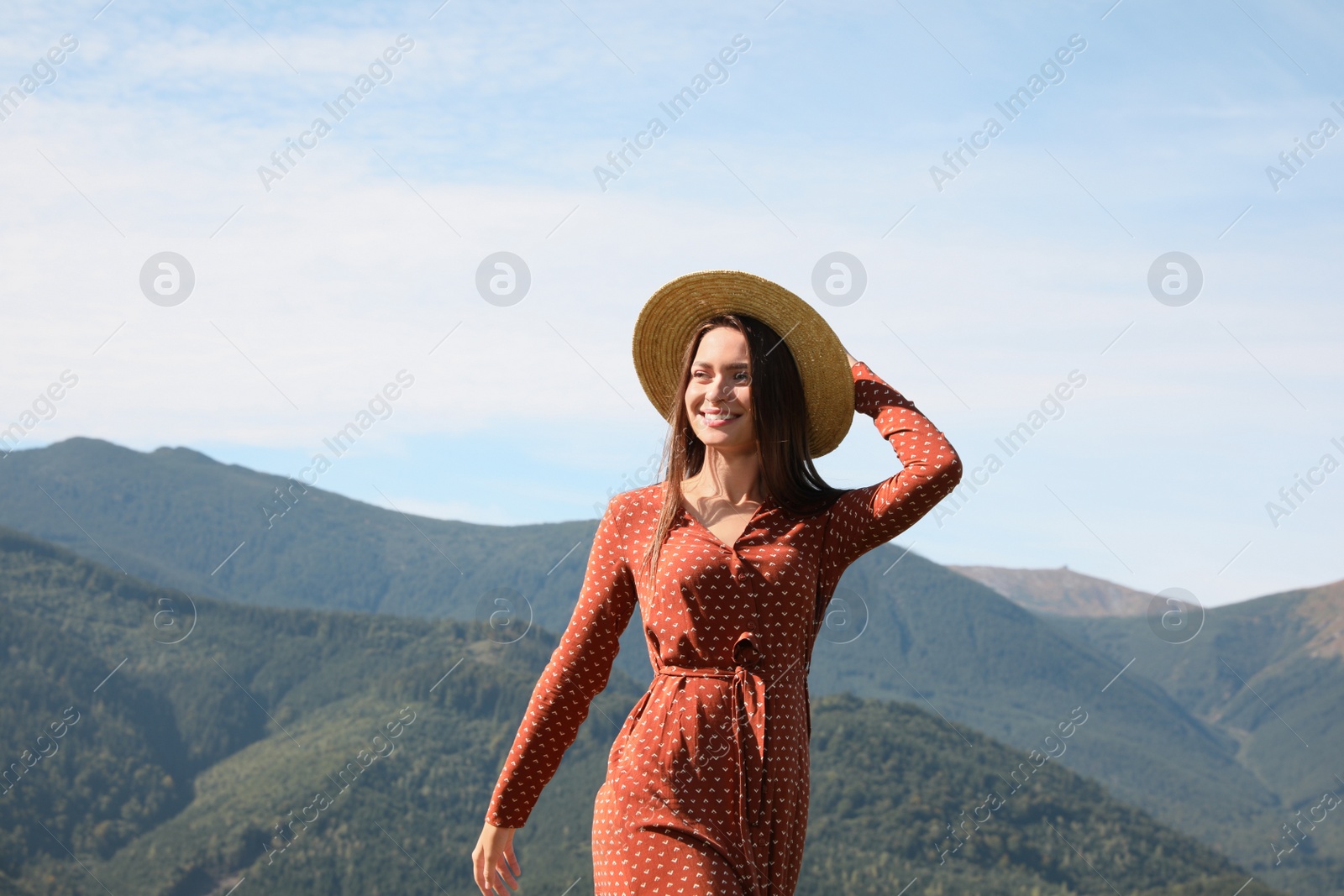 Photo of Young woman with straw hat walking in beautiful mountains on sunny day