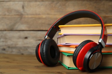 Photo of Books and modern headphones on wooden table, closeup