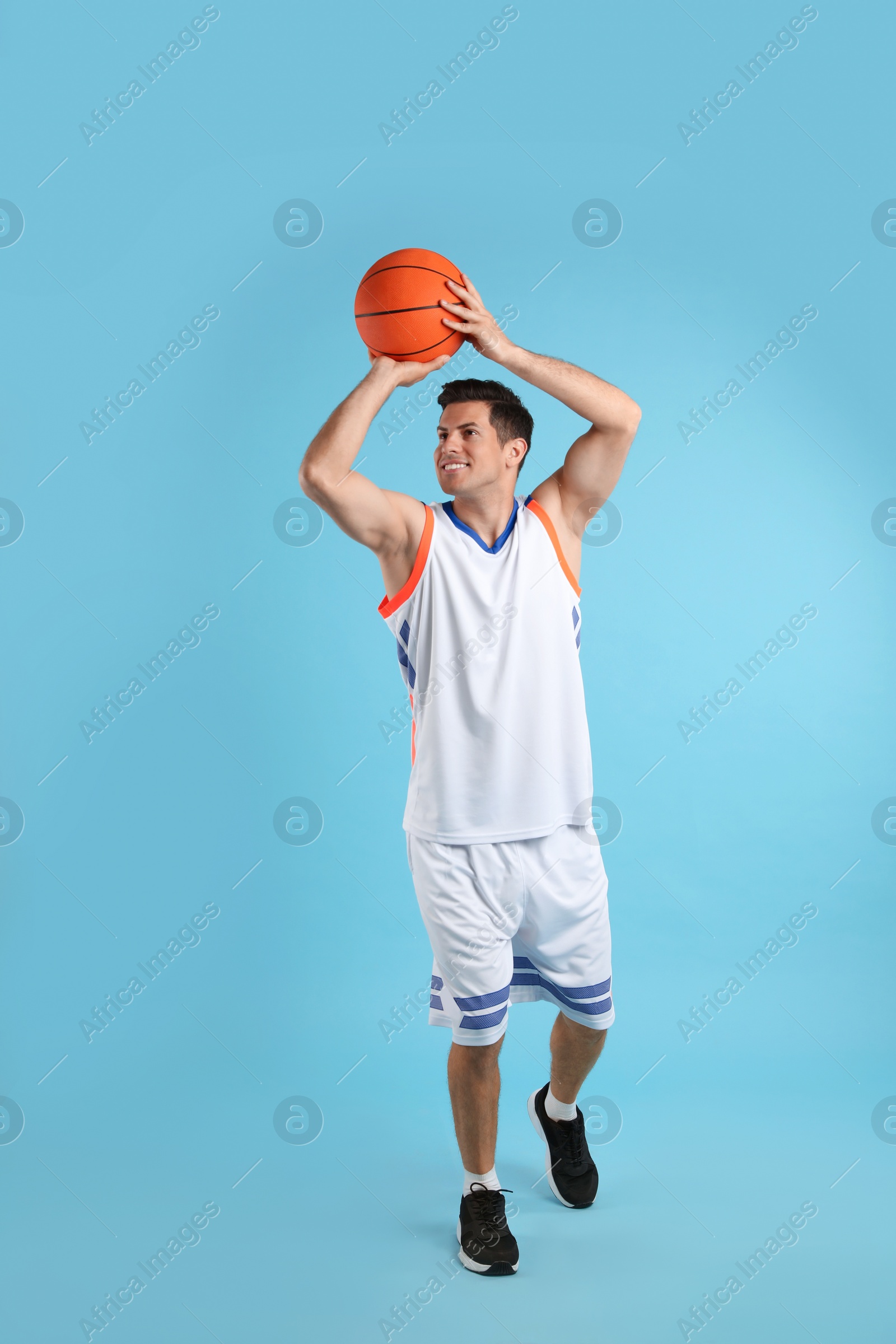 Photo of Professional sportsman playing basketball on light blue background