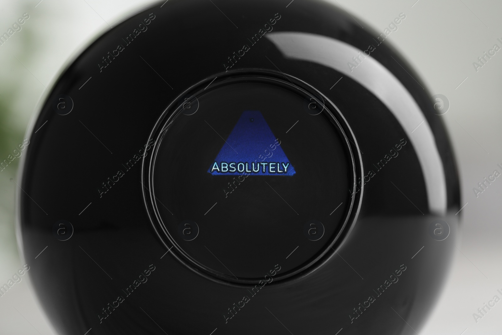 Photo of Magic eight ball with prediction Absolutely on light background, closeup