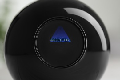 Photo of Magic eight ball with prediction Absolutely on light background, closeup