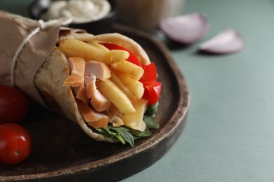 Photo of Delicious pita wrap with chicken, french fries and pepper on light blue background, closeup. Space for text