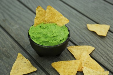 Delicious guacamole made of avocados and nachos on wooden table, closeup