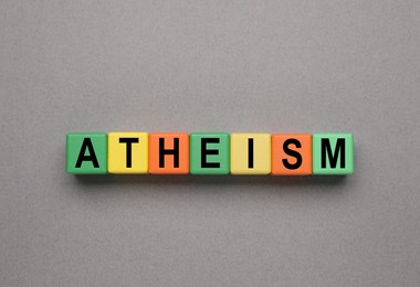 Image of Word Atheism made of wooden cubes with letters on grey table, top view