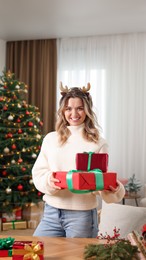 Photo of Young woman with beautifully wrapped Christmas gifts at home