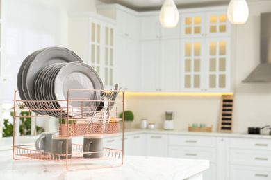 Photo of Drying rack with clean dishes on table in kitchen. Space for text