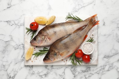 Photo of Fresh raw perches and ingredients on white marble table, top view. River fish