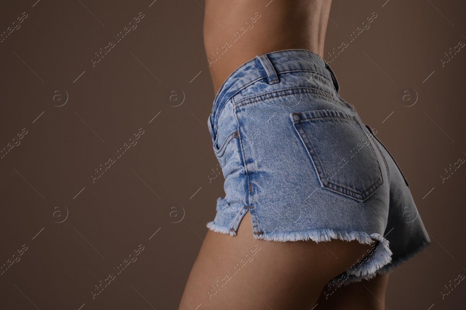 Photo of Closeup view of slim woman with smooth skin in denim shorts on beige background, space for text. Cellulite problem concept