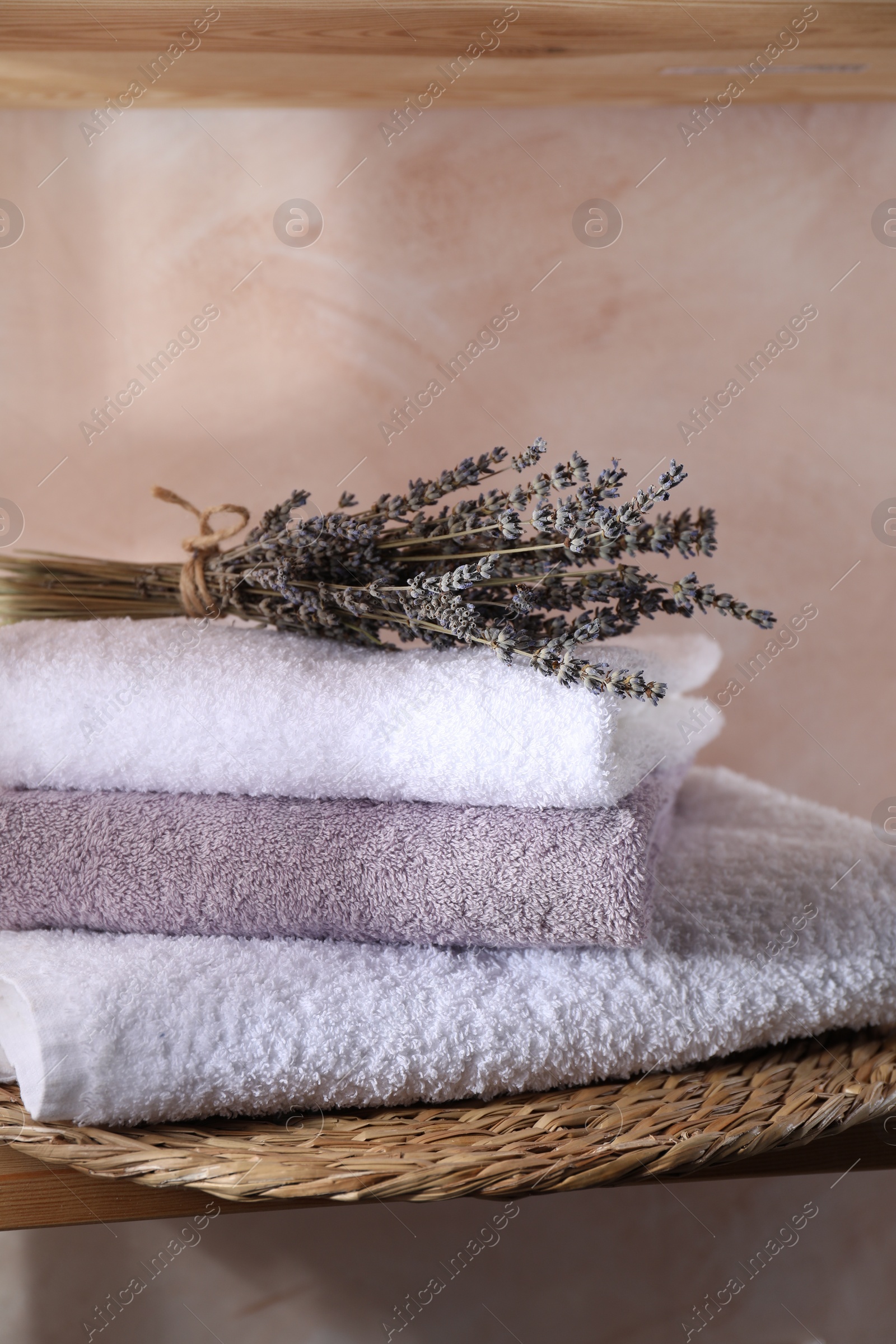 Photo of Stacked soft towels and lavender on shelf indoors