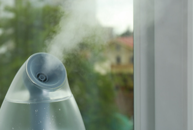 Modern air humidifier near window indoors, closeup. Space for text