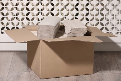 Photo of Cardboard box with paper napkins on floor indoors