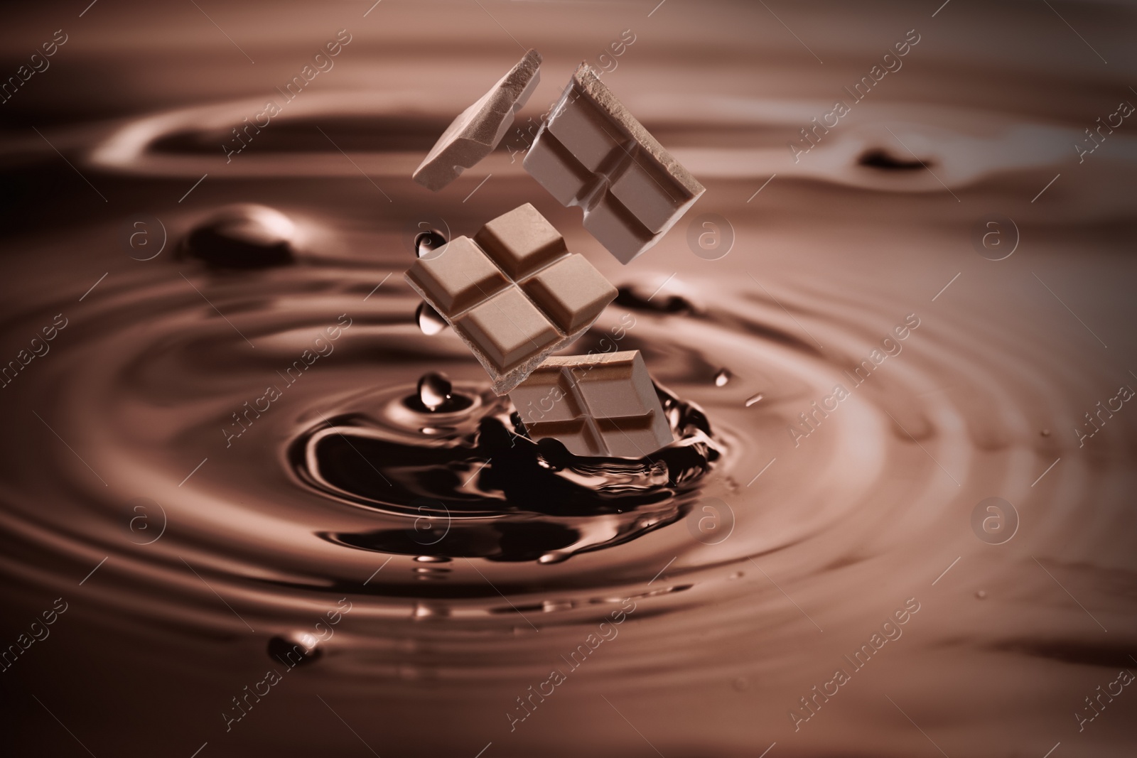 Image of Yummy melted chocolate splashing with falling pieces as background