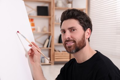 Photo of Man painting on white canvas in studio