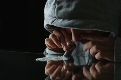 Photo of Drug addict taking cocaine at table, closeup view