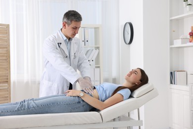 Photo of Gastroenterologist examining patient with stomach pain on couch in clinic