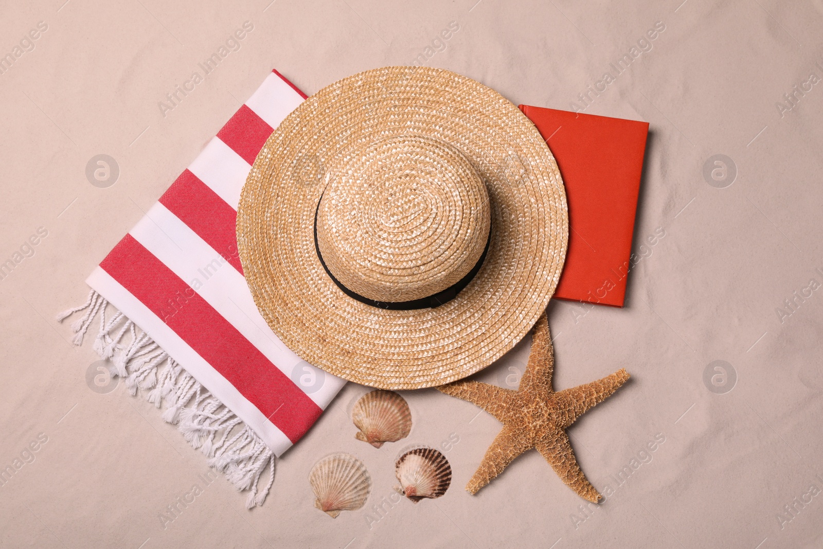 Photo of Beach towel, hat, book, starfish and sea shells on sand, flat lay