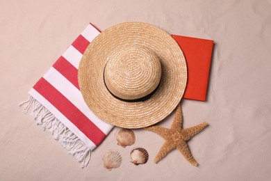 Beach towel, hat, book, starfish and sea shells on sand, flat lay