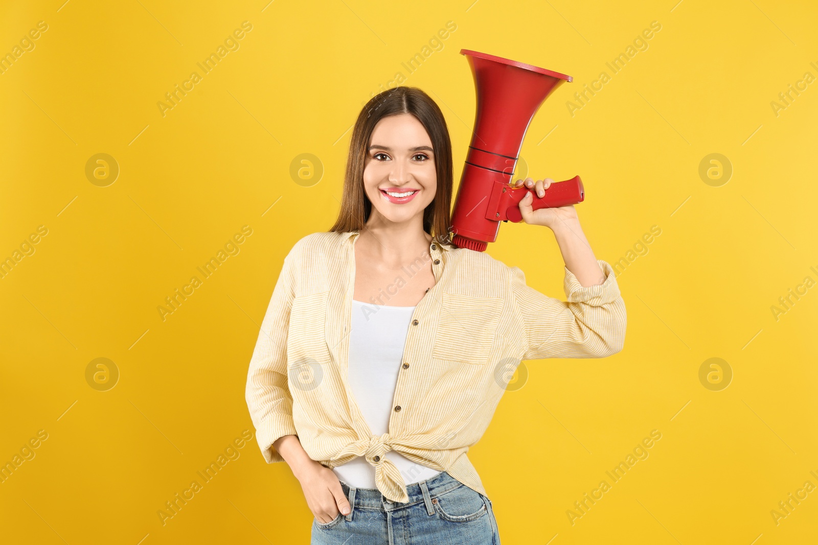 Photo of Young woman with megaphone on yellow background