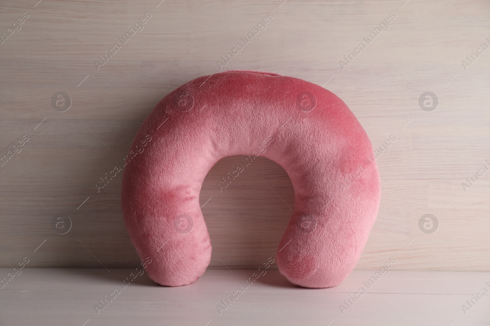 Photo of Pink travel pillow on light wooden background