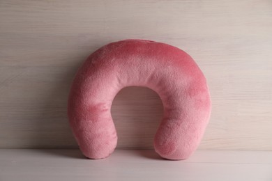 Photo of Pink travel pillow on light wooden background