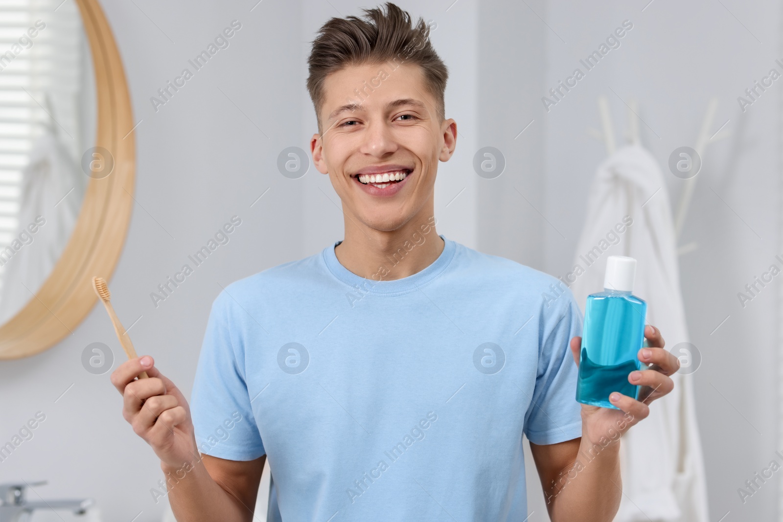 Photo of Young man with mouthwash and toothbrush in bathroom