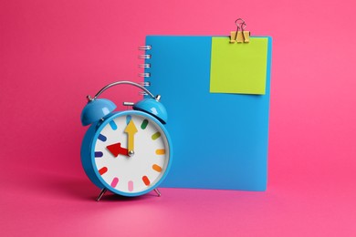 Photo of Alarm clock and notebook with blank reminder note on pink background, space for text