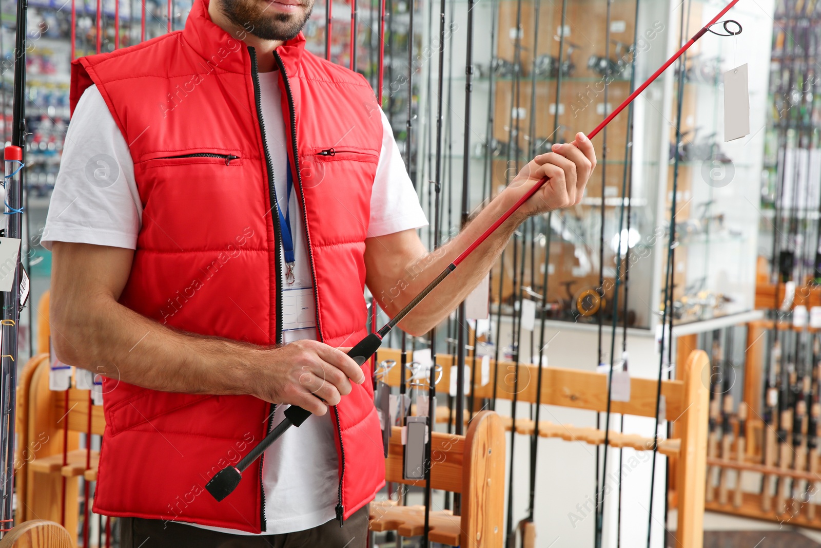 Photo of Salesman with fishing rod in sports shop, closeup