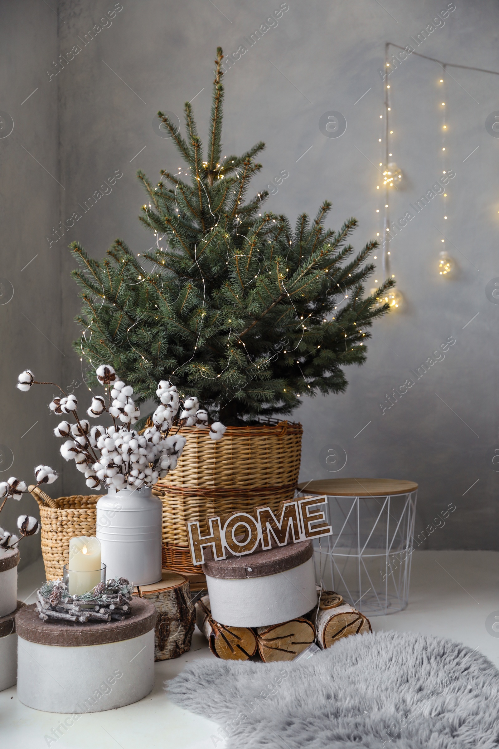 Photo of Little Christmas tree with fairy lights in bedroom interior